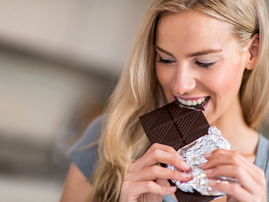 Frau isst Schokolade - ist Zucker ungesund für die Haut?
