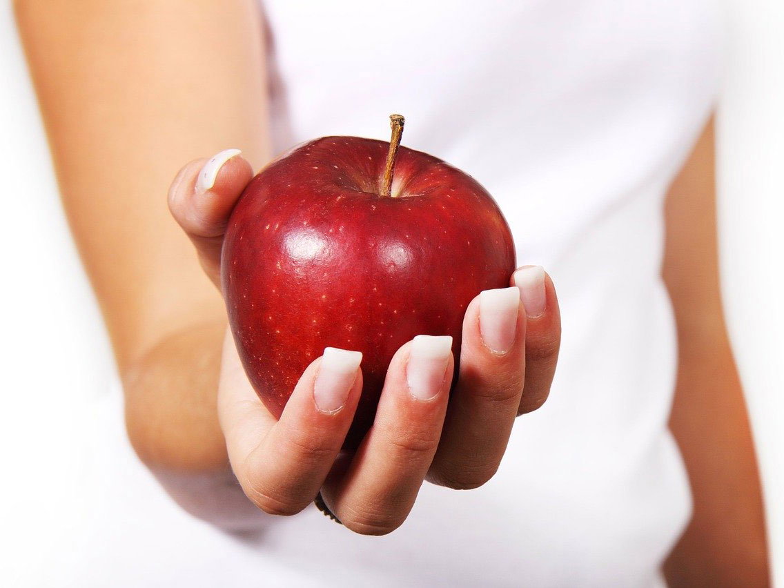 Frau mit Apfel: Gesund und fit bleiben im Homeoffice