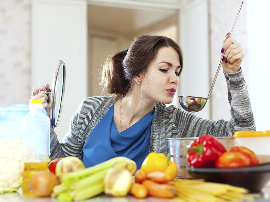 Frau kocht und probiert von einer Kelle - So kochen Sie kalorienarm und gesund