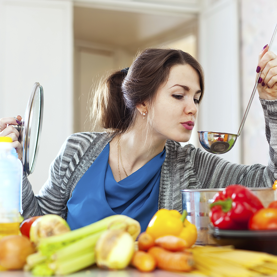 Frau kocht und probiert von einer Kelle - So kochen Sie kalorienarm und gesund