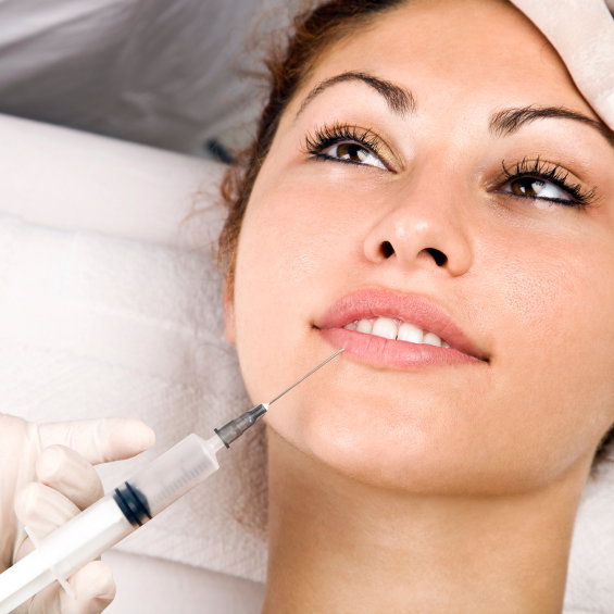 Frau bekommt auf einem Arztstuhl Botox gespritzt