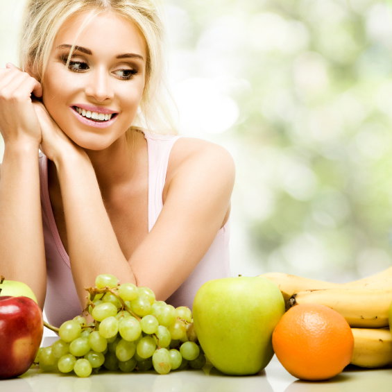 Frau kann sich nicht entscheiden, welches Obst sie essen soll - sie ernährt sich sehr gesund