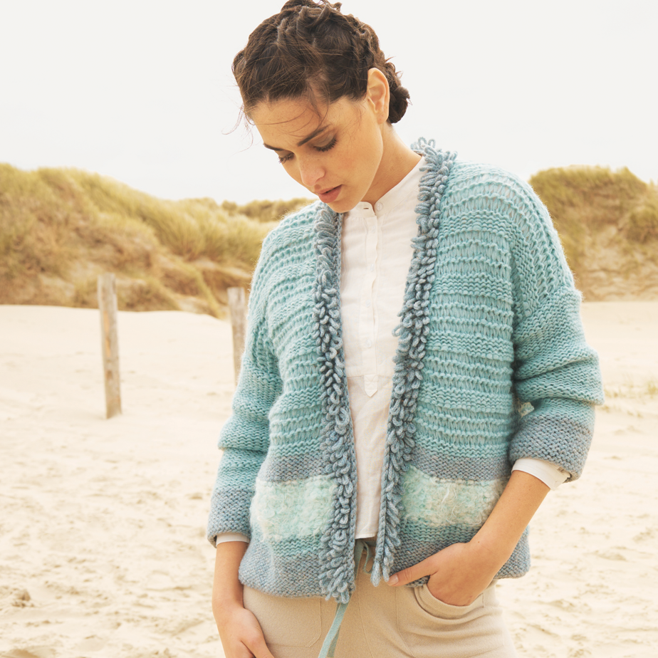Frau am Strand trägt Kurzjacke mit stylischer Wollbordüre