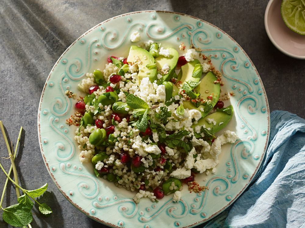 perlgraupensalat mit Granatapfel und Feta auf einem Teller, angerichtet mit Avocado