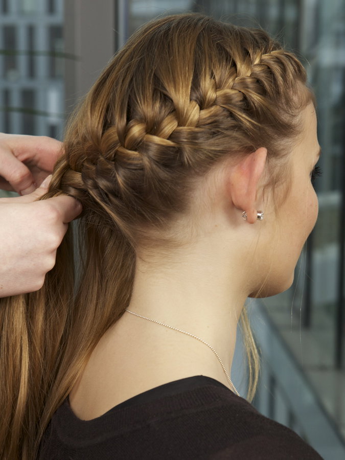 Frau flechtet einer Frau die Haare
