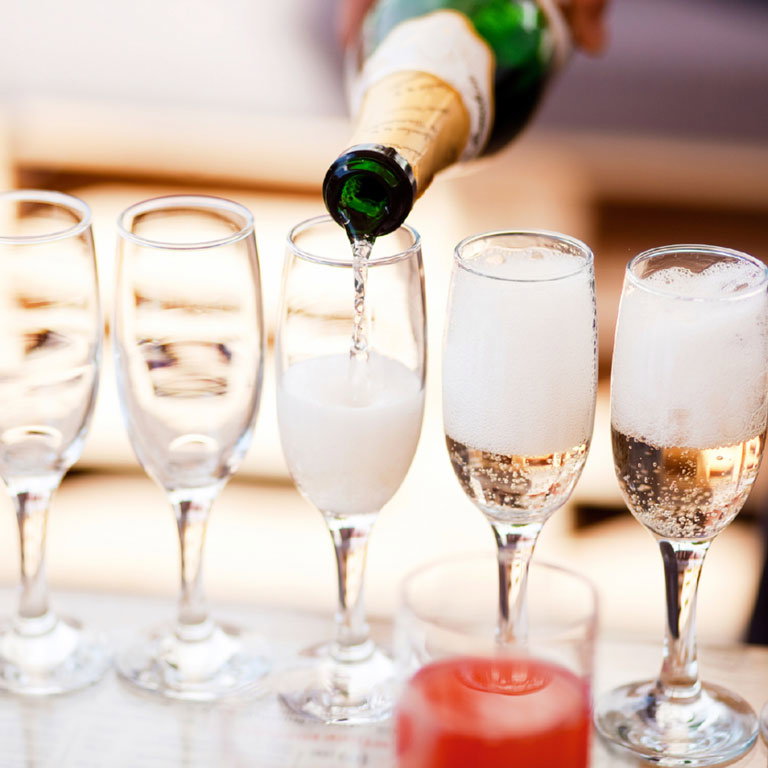Eingießen von Sekt aus Sektflasche in mehrere Sektgläser