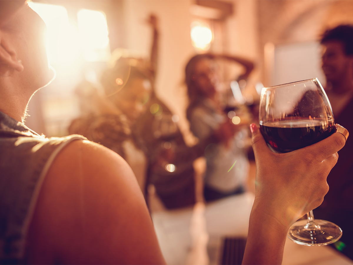 Frau trinkt ein Glas Rotwein. Gegen einen Kater helfen diese Tipps.
